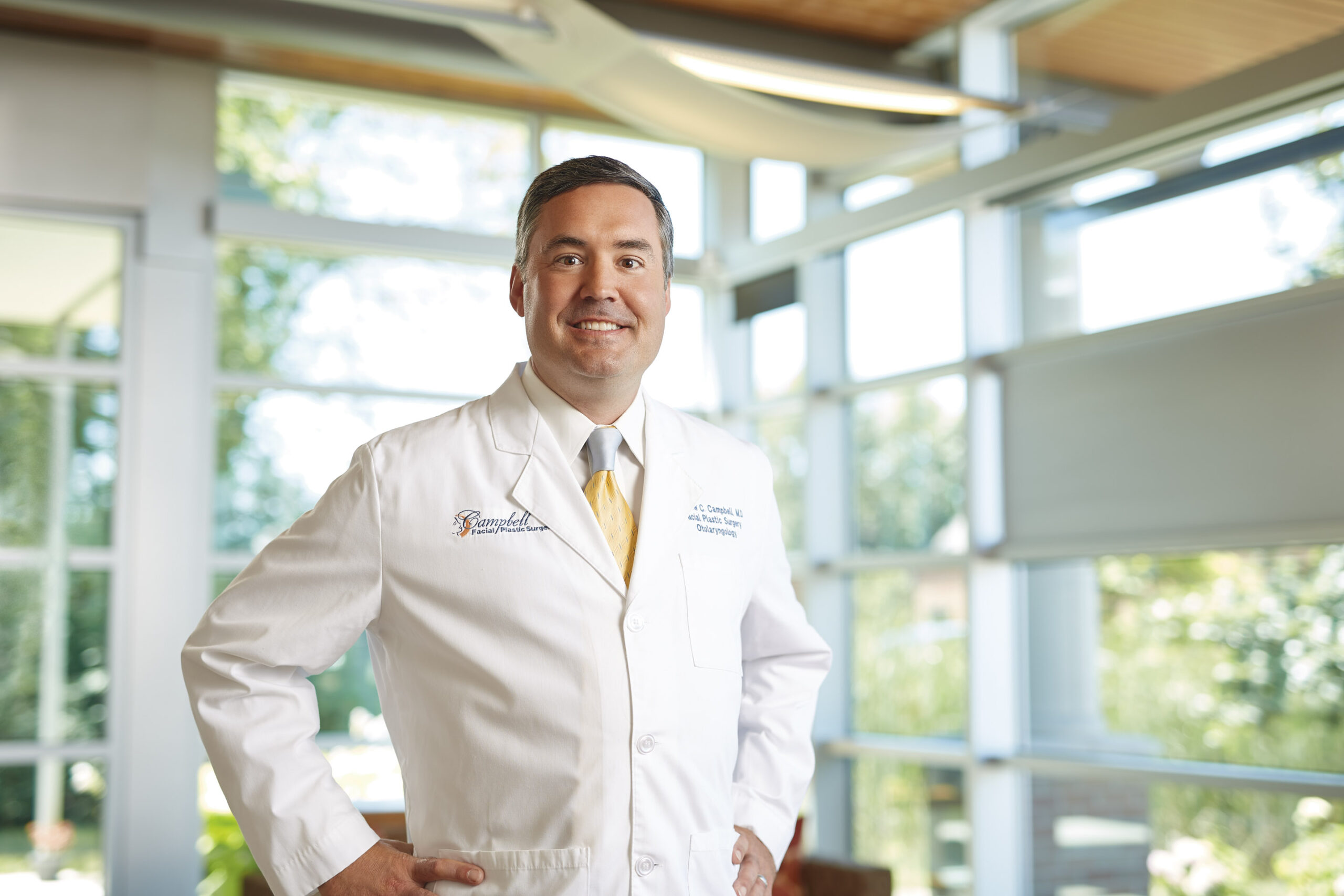 Dr. Andrew Campbell smiling and posing in front of windows at Quintessa