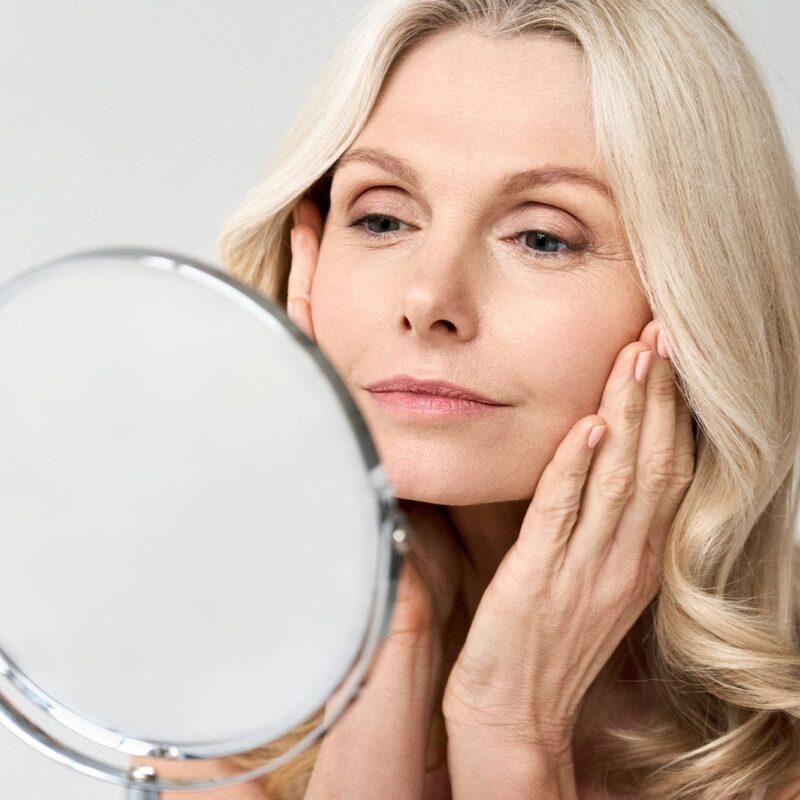 woman looking in the mirror after her facelift procedure in milwaukee